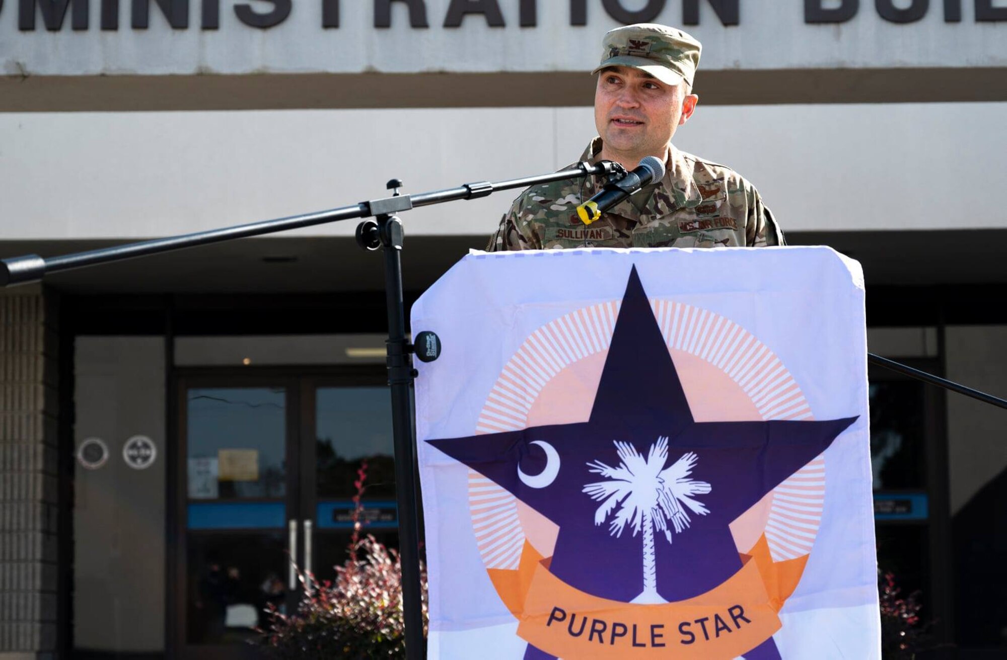 A photo of an Airman speaking at a podium.