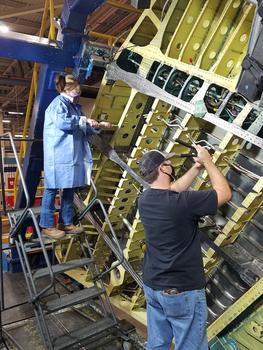 Photo shows two individuals working on an aircraft