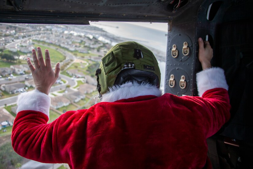 A Marine dressed as Santa Claus waves from a helicopter.