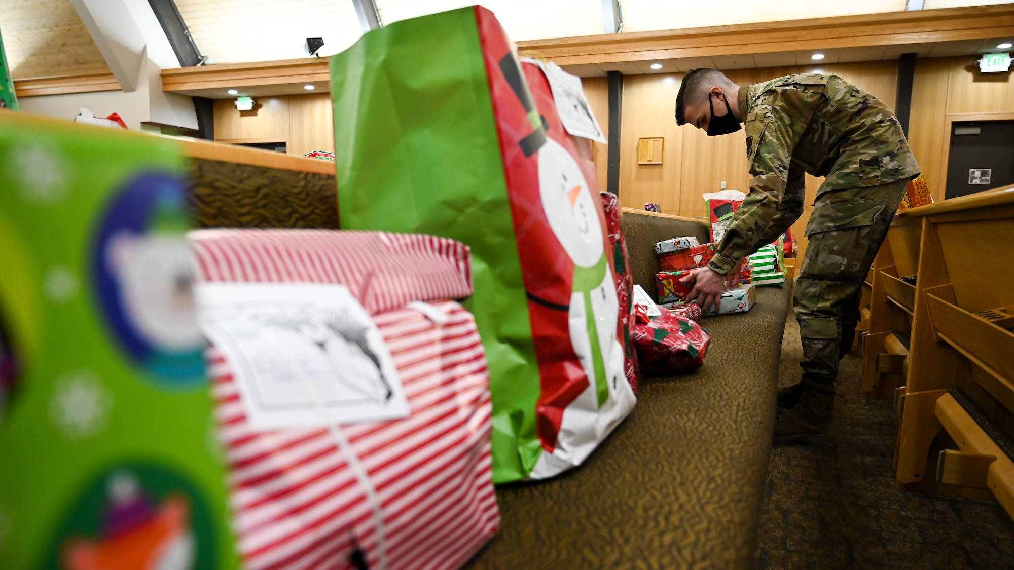 Volunteers sort Angel Tree wrapped gifts on pews inside the base chapel.