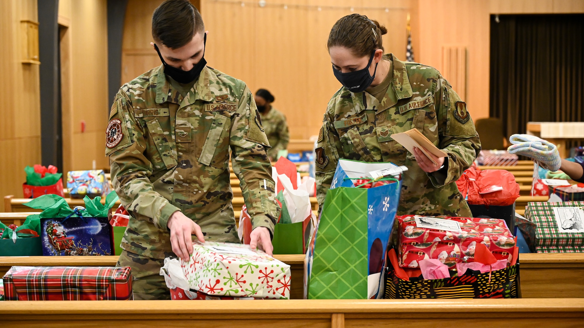 Volunteers sort Angel Tree wrapped gifts on pews inside the base chapel.