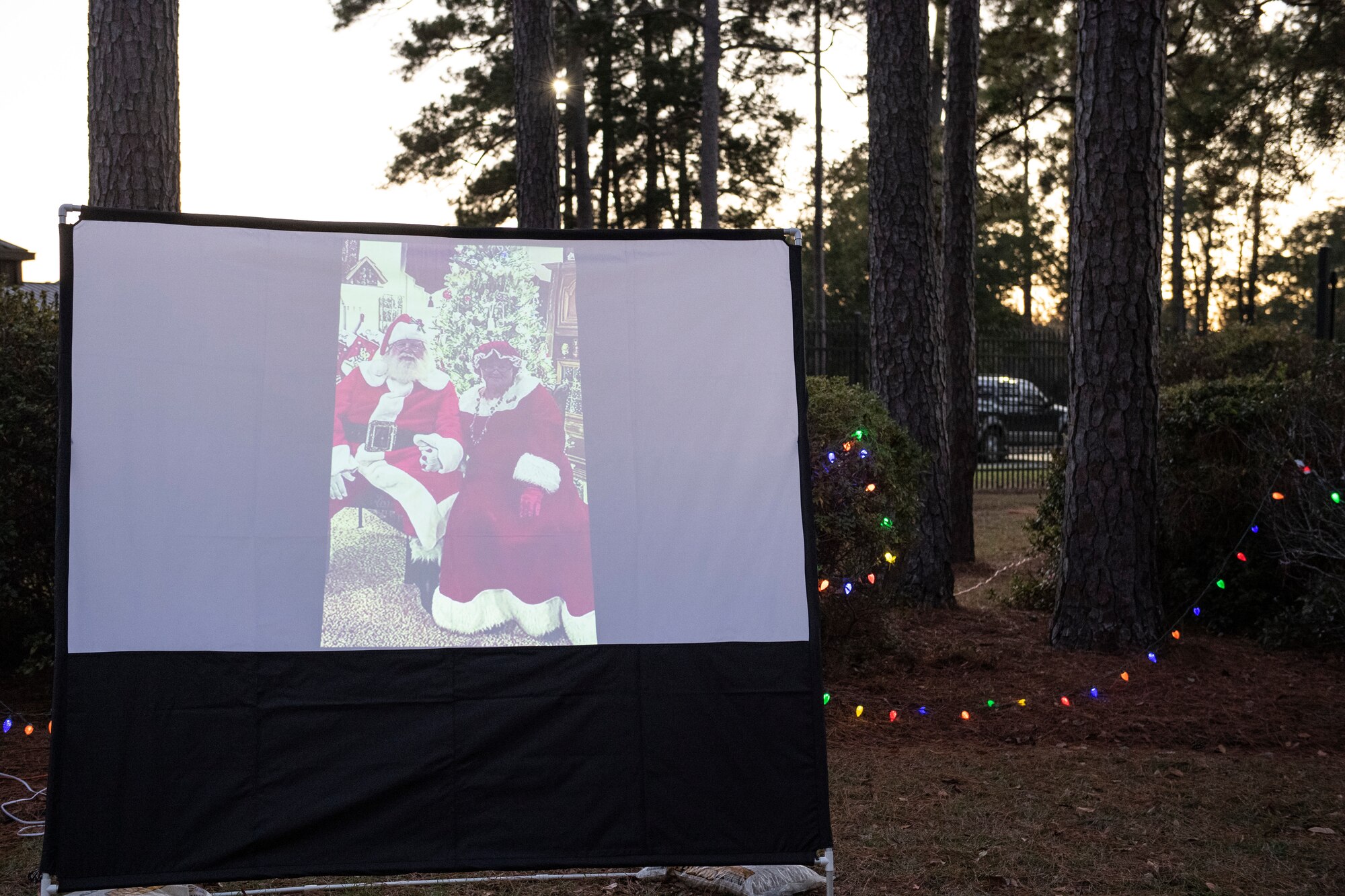 A photo of Mr. and Mrs. Santa Claus on a video projector during a drive-through holiday dinner.