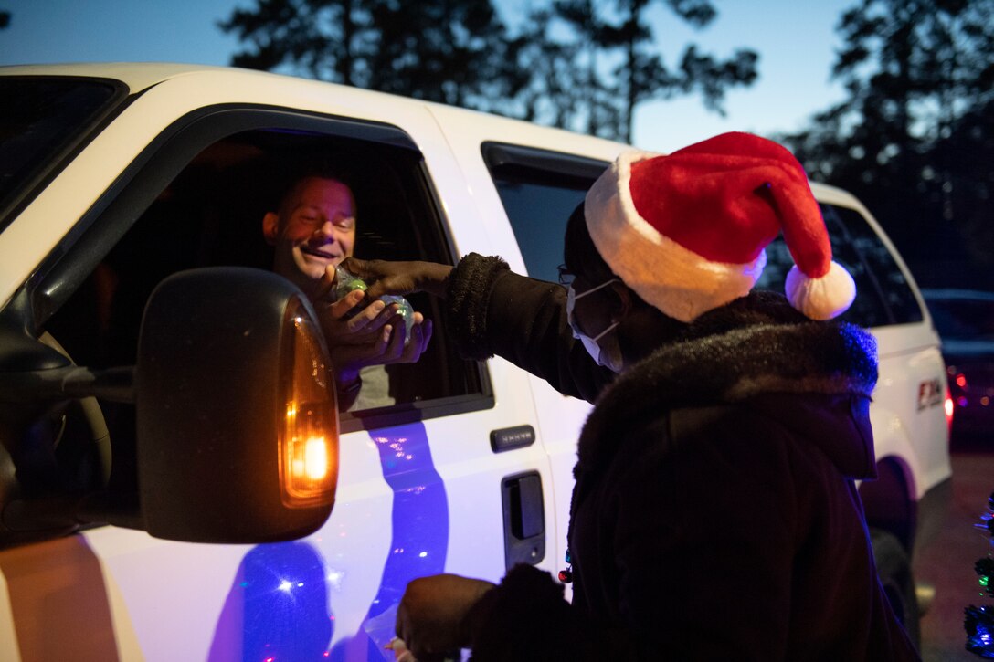 A photo of Sharon Register, A&FRC flight chief, handing out candy to a family during a drive-through holiday dinner.