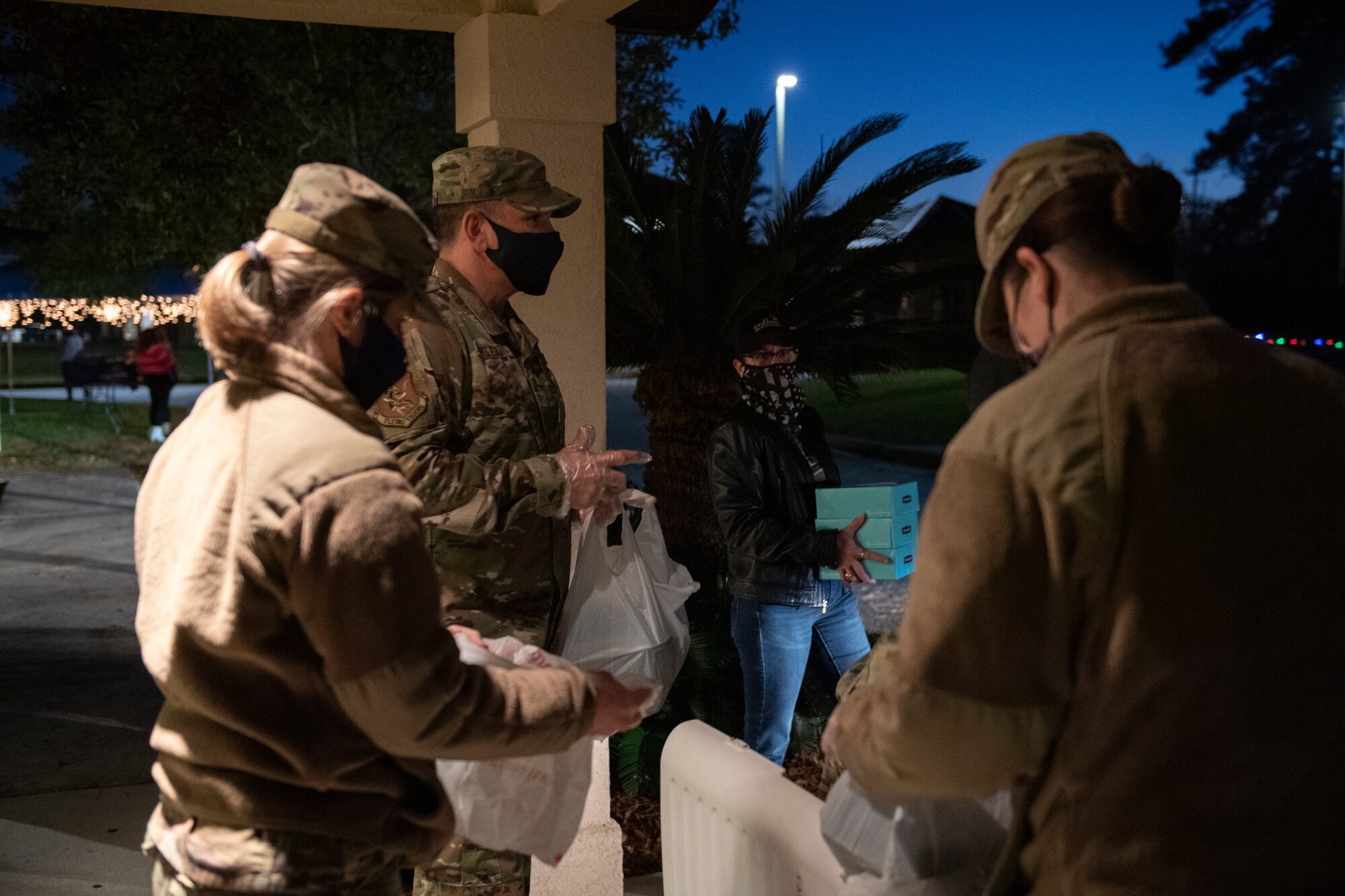 A photo of Airmen handing out food during a drive-through holiday dinner.