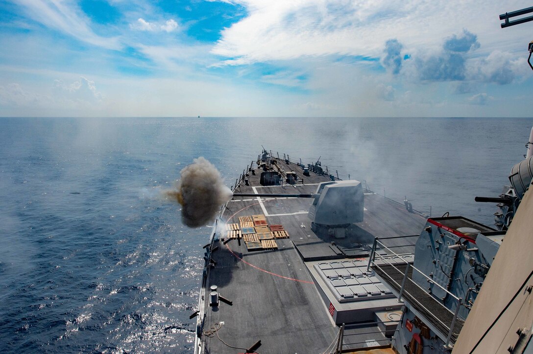 A ship fires a gun over the water.