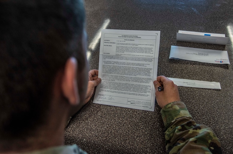 An Airman reads a form to register as a bone marrow donor.