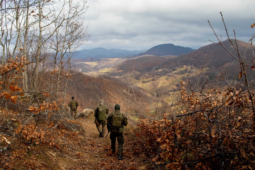 Soldiers walk down a mountain trail.