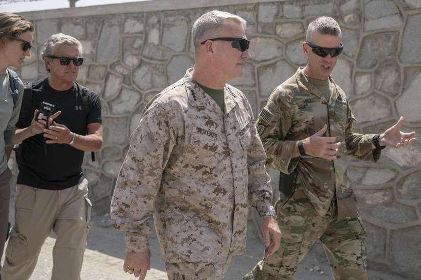 Two men in military uniforms converse while walking.