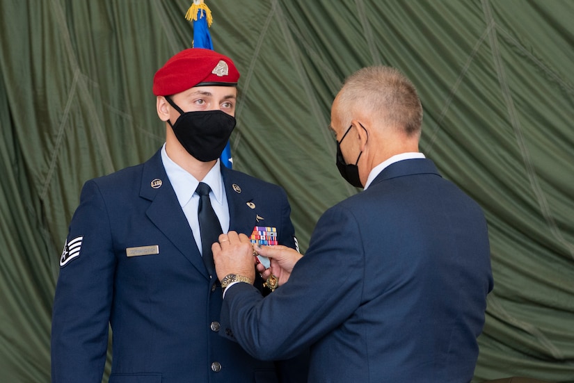 An airman stands while his father pins an award on his uniform.