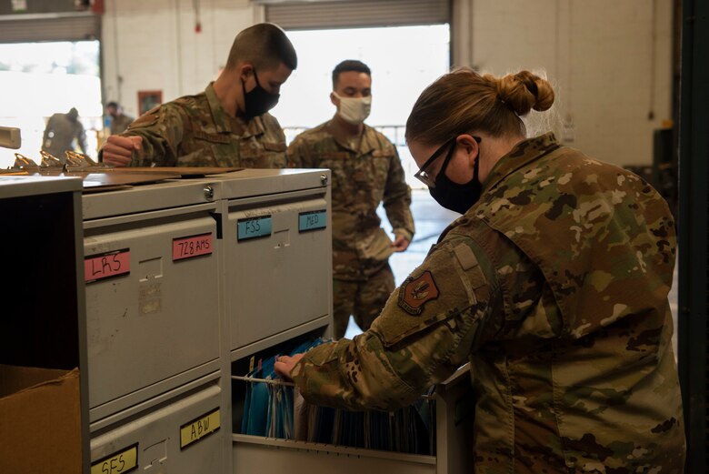 A female logistics Airman looks through a filing cabinet for inventory receipts.