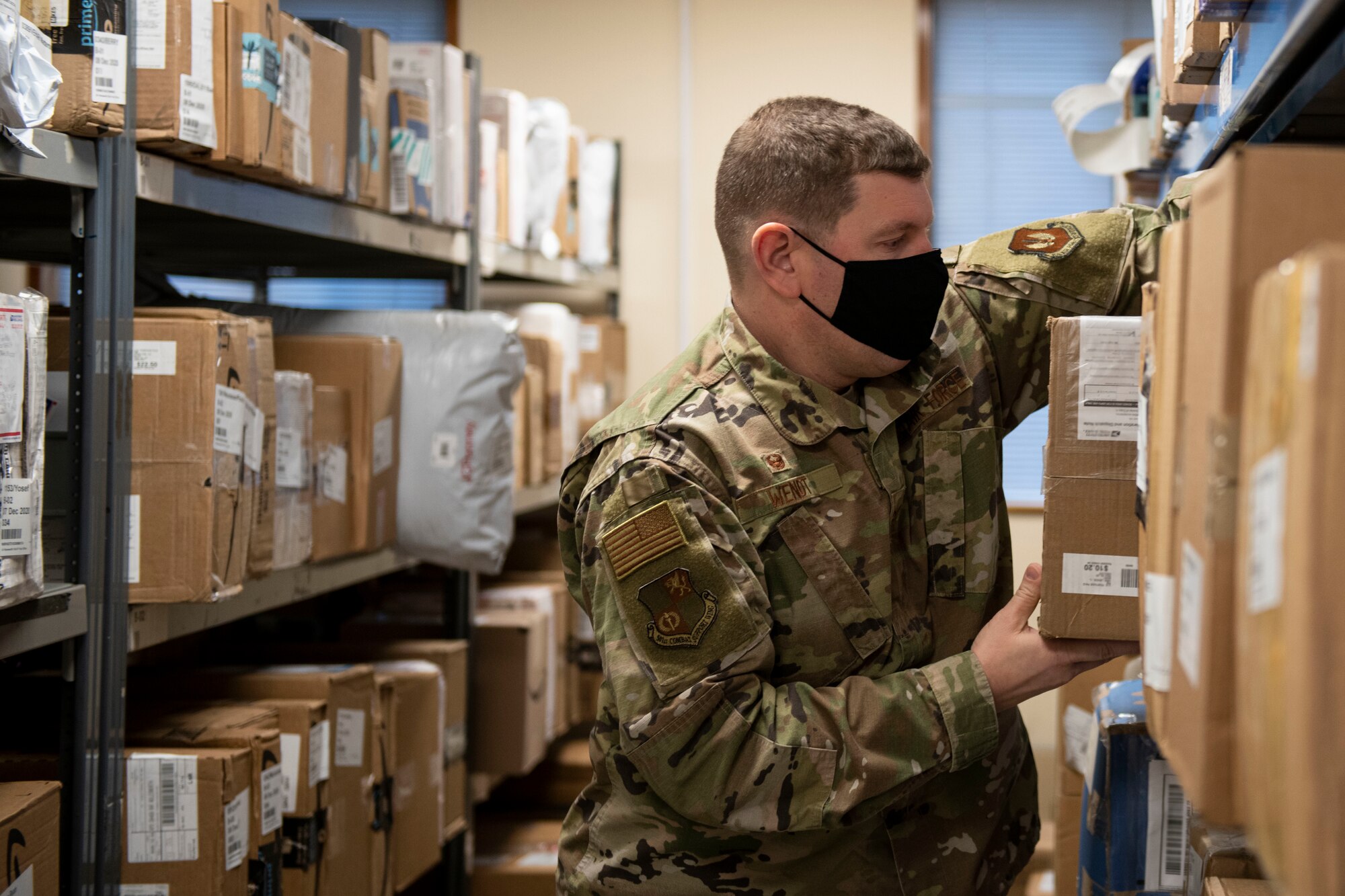 U.S. Air Force Col. Kurt Wendt, 501st Combat Support Wing commander, retrieves a package for a customer at the Royal Air Force Molesworth Post Office, England, Dec. 9, 2020. Airmen and civilians have volunteered at the post office to help with the influx of packages during the holiday season. (U.S. Air Force photo by Senior Airman Jennifer Zima)