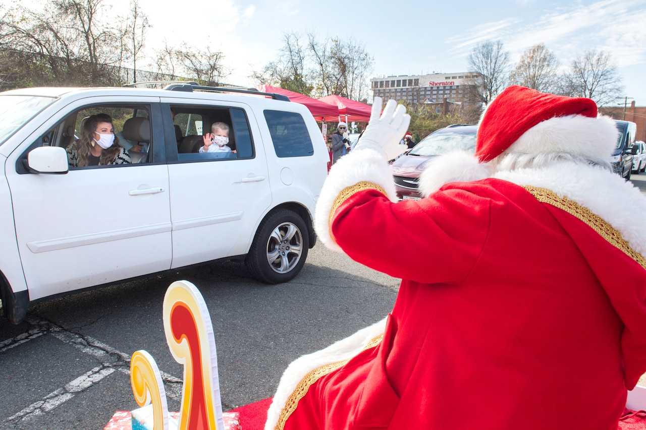 Santa waves to a masked family in an SUV.