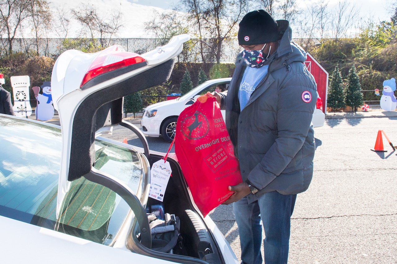 A man puts a full bag into a trunk.