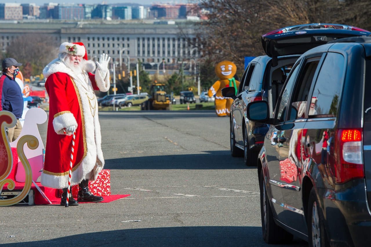 Santa waves to two minivans.