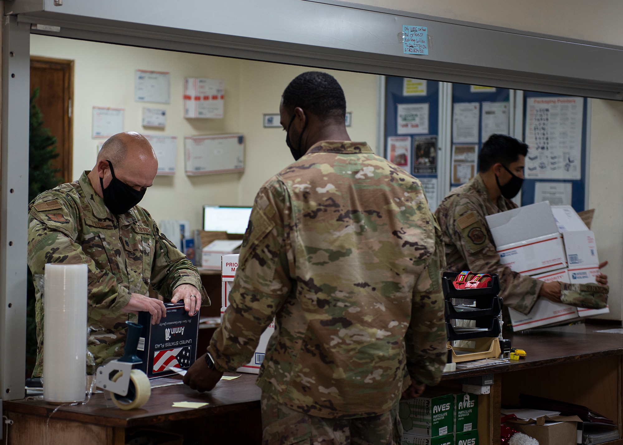 An Airman assigned to the 380th Expeditionary Force Support Squadron assists customers with preparing packages for delivery at Al Dhafra Air Base (ADAB), United Arab Emirates, Dec. 8, 2020. The ADAB post office provides postal service to patrons consisting of U.S. Air Force personnel as well as joint and coalition partners. (U.S. Air Force photo by Senior Airman Bryan Guthrie)
