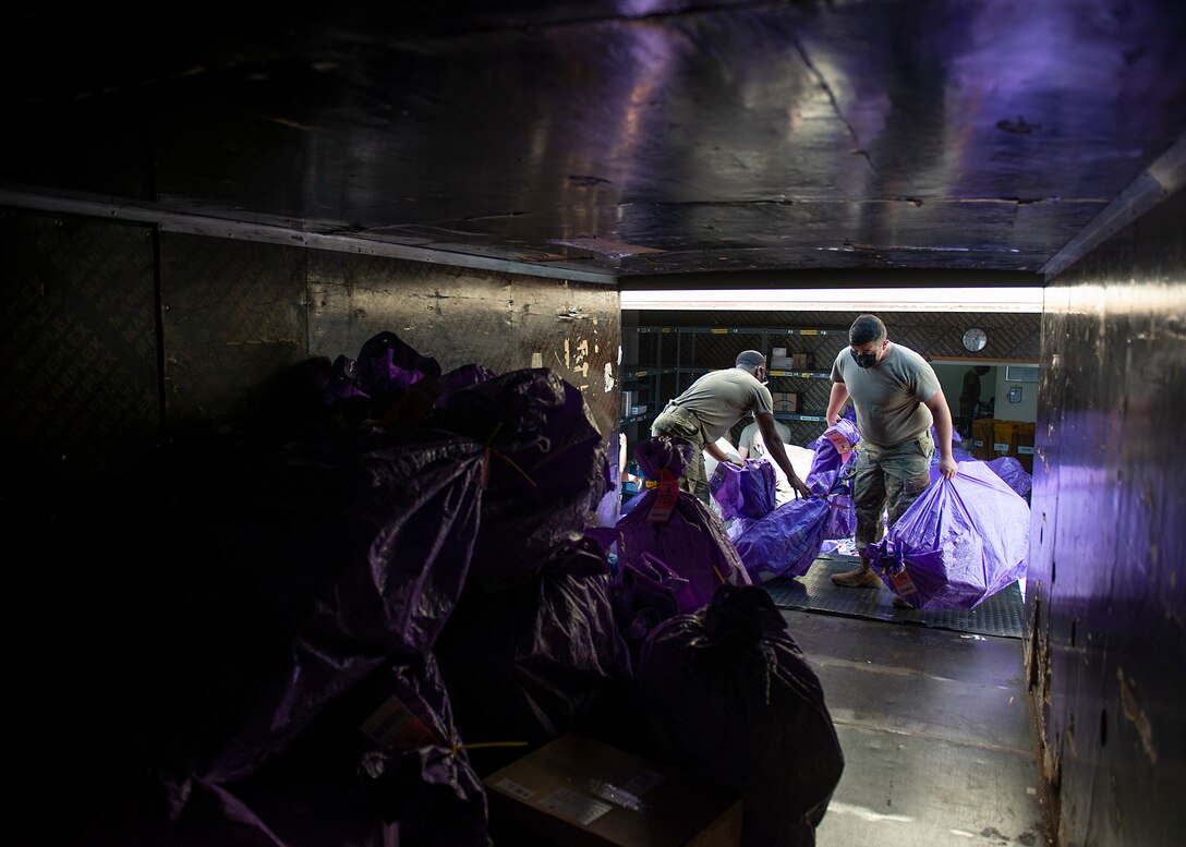 U.S. Air Force Staff Sgt. Louis Fields (left), 380th Expeditionary Force Support Squadron postal clerk, and Senior Airman Jesus Castrejon-Martinez (right), 380th Expeditionary Logistics Readiness Squadron log planner, load packages into a truck at Al Dhafra Air Base (ADAB), United Arab Emirates (UAE), Dec. 8, 2020. The ADAB post office works directly with Dubai Mail Control Activity through contracts with the UAE. (U.S. Air Force photo by Senior Airman Bryan Guthrie)