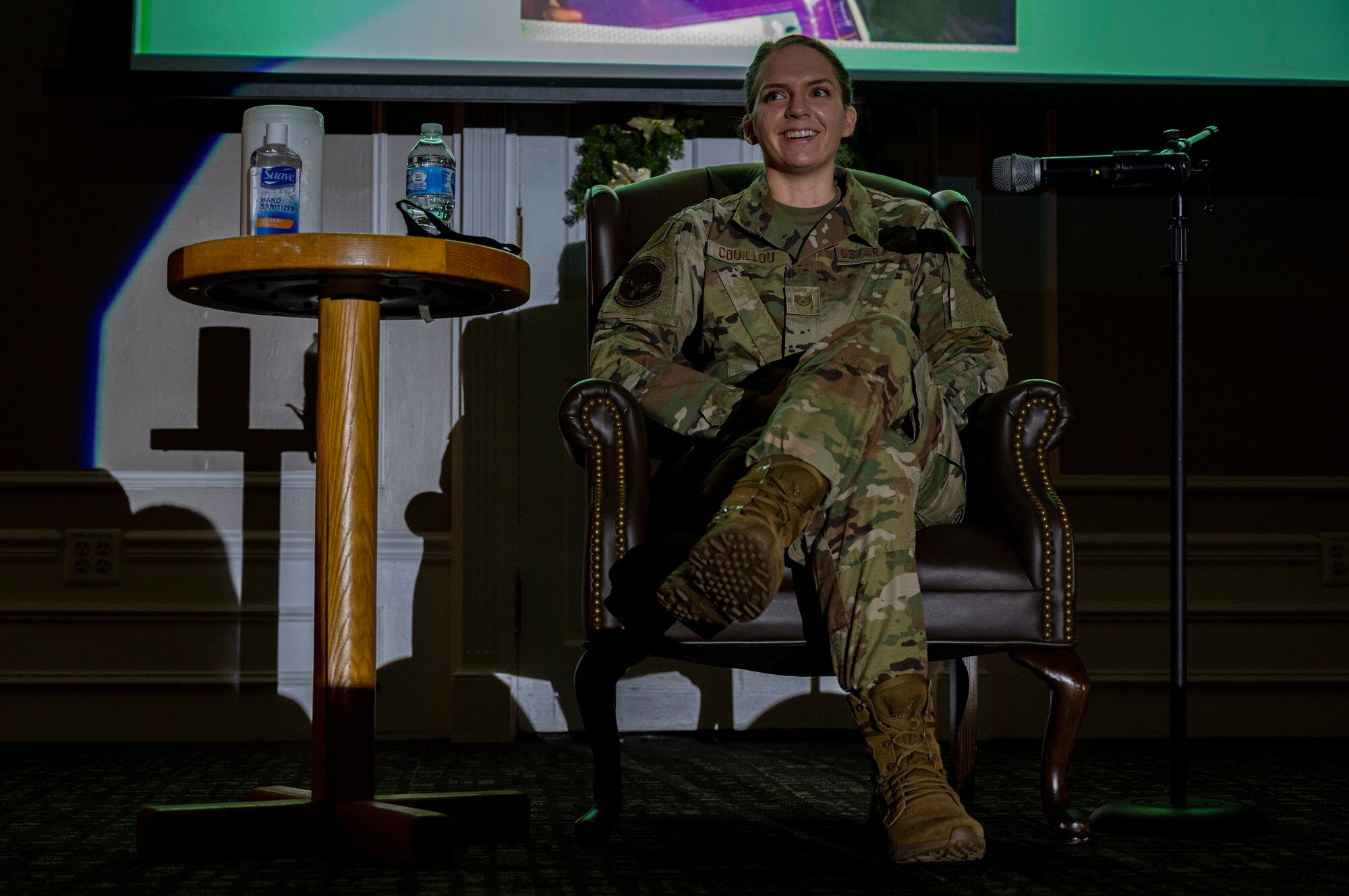 A photo of an Airman sitting on a stage with a spotlight.