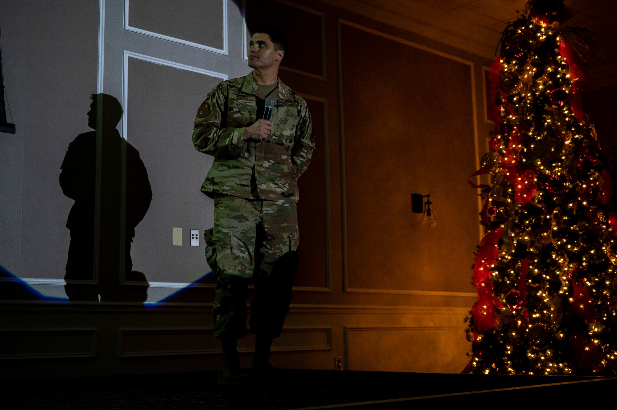 A photo of an Airman standing on a stage with a spotlight.