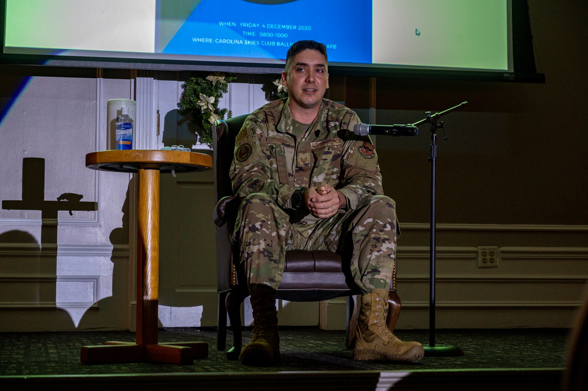 A photo of an Airman sitting on a stage with a spotlight.