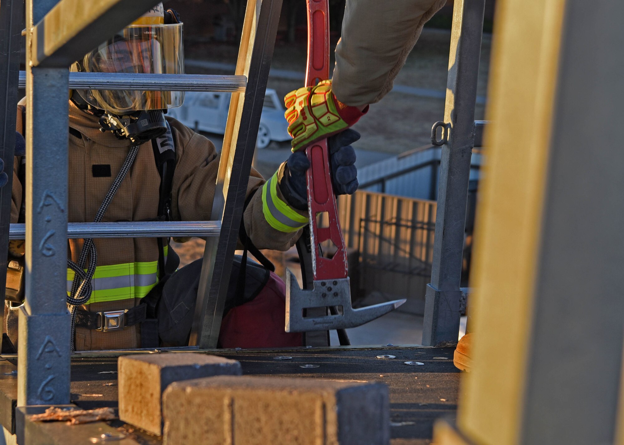 U.S. Air Force Tech Sgt. Eugene Dotson, 312th Training Squadron fire protection instructor, helps adjust the axe of Air National Guard Airman 1st Class Geovannie Rios-Santos, 312th Training Squadron fire protection student, while Rios-Santos transitions from the ladder to the rooftop for his vertical ventilation training exercise at the Louis F. Garland Department of Defense Fire Academy on Goodfellow Air Force Base, Texas, Dec. 10, 2020. At the 312th TRS, Rios-Santos’ and every member’s education was key to developing the next generation of professionals who will ensure worldwide dominance. (U.S. Air Force photo by Senior Airman Abbey Rieves)