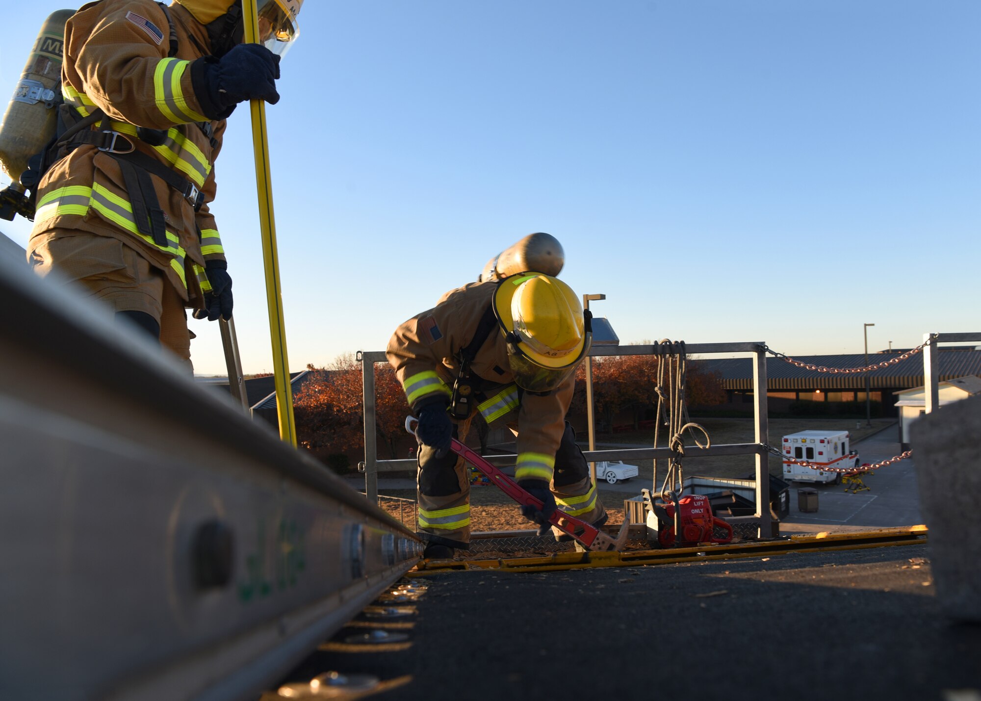 U.S. Air National Guard Airman 1st Class Geovannie Rios-Santos and Air Force Airman Nathan Lott, 312th Training Squadron fire protection students, combine joint service skills while carving out a hole on a combustible roof during their vertical ventilation training at the Louis F. Garland Department of Defense Fire Academy on Goodfellow Air Force Base, Texas, Dec. 10, 2020. Lott’s first cut into the roof was on the furthest downwind side of the opening from the ladder to prevent hot and toxic gases from blowing into Rios-Santos and himself. (U.S. Air Force photo by Senior Airman Abbey Rieves)