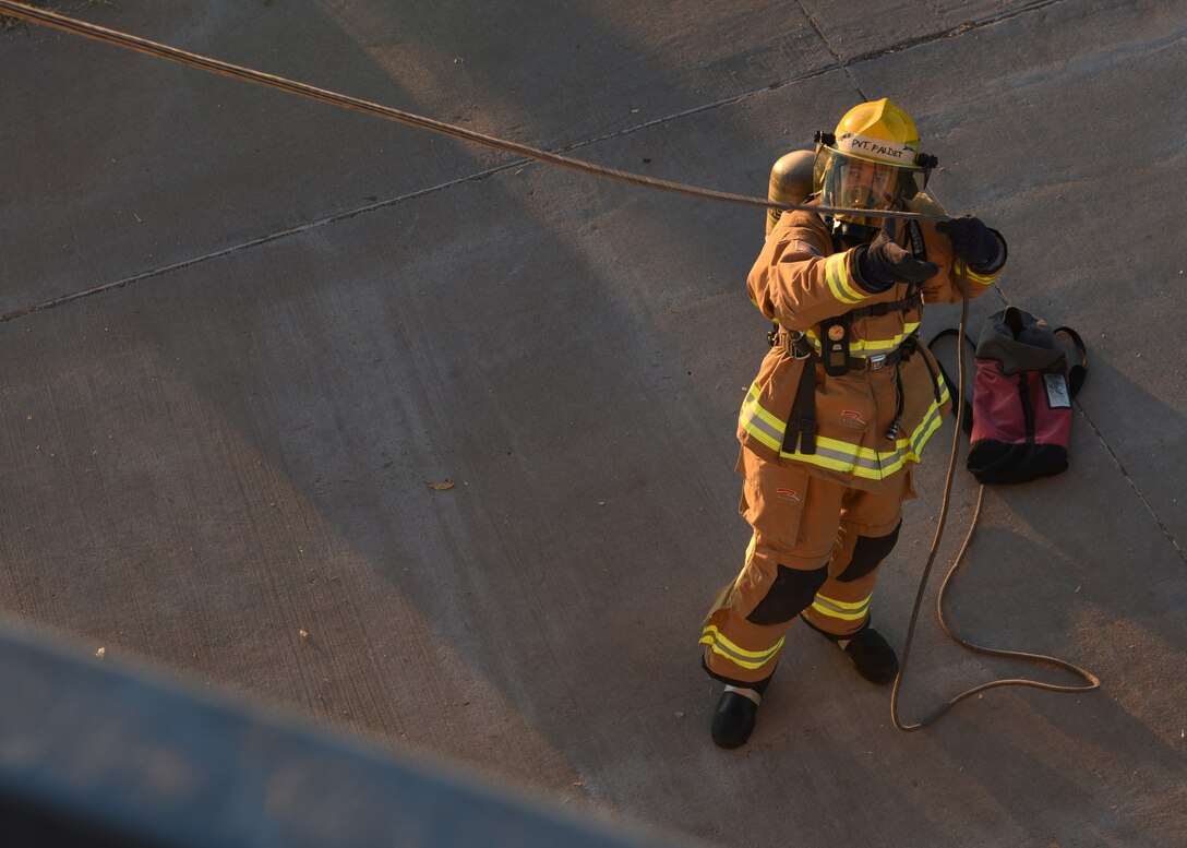 U.S. Marine Corps PVT. David Faldet, 312th Training Squadron fire protection student, pulls a rope taught, during a vertical ventilation partner training exercise at the Louis F. Garland Department of Defense Fire Academy on Goodfellow Air Force Base, Texas, Dec. 12, 2020. Faldet’s rope leveraged a chain saw and additional fire and rescue supplies to the artificial rooftop during the joint forces training simulation. (U.S. Air Force photo by Senior Airman Abbey Rieves)