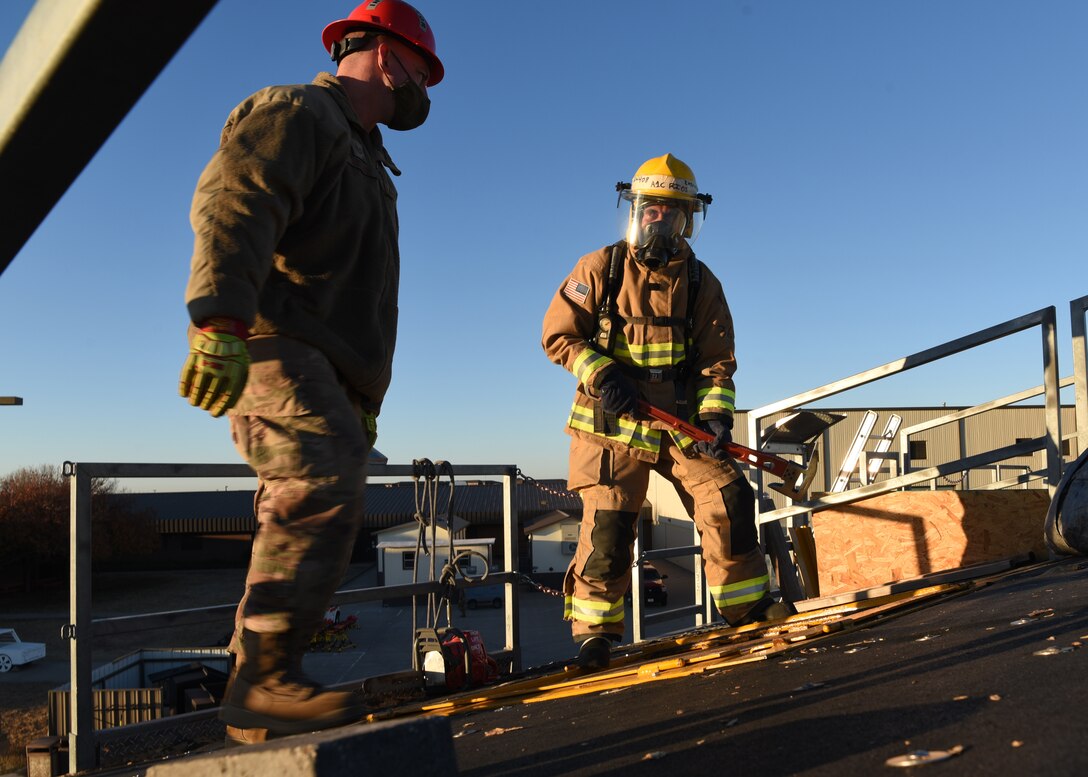 U.S. Air Force Tech Sgt. Eugene Dotson, 312th Training Squadron fire protection instructor, coaches Air National Guard Airman 1st Class Geovannie Rios-Santos, 312th Training Squadron fire protection student, on weight distribution and proper ways to quickly remove the combustible roof during a vertical ventilation training exercise at the Louis F. Garland Department of Defense Fire Academy on Goodfellow Air Force Base, Texas, Dec. 10, 2020. Vertical ventilation was an offensive strategy that students utilized to create a 4x4 foot exhaust port in order to remove hot and toxic air from inside the burning building. (U.S. Air Force photo by Senior Airman Abbey Rieves)