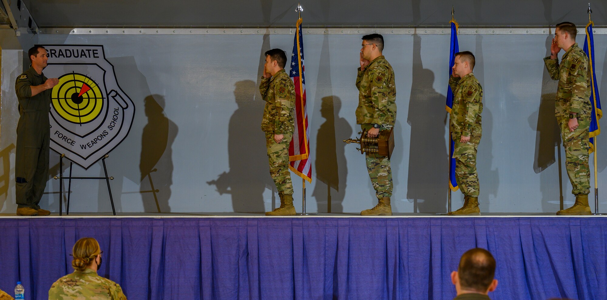 Airmen salute on stage.