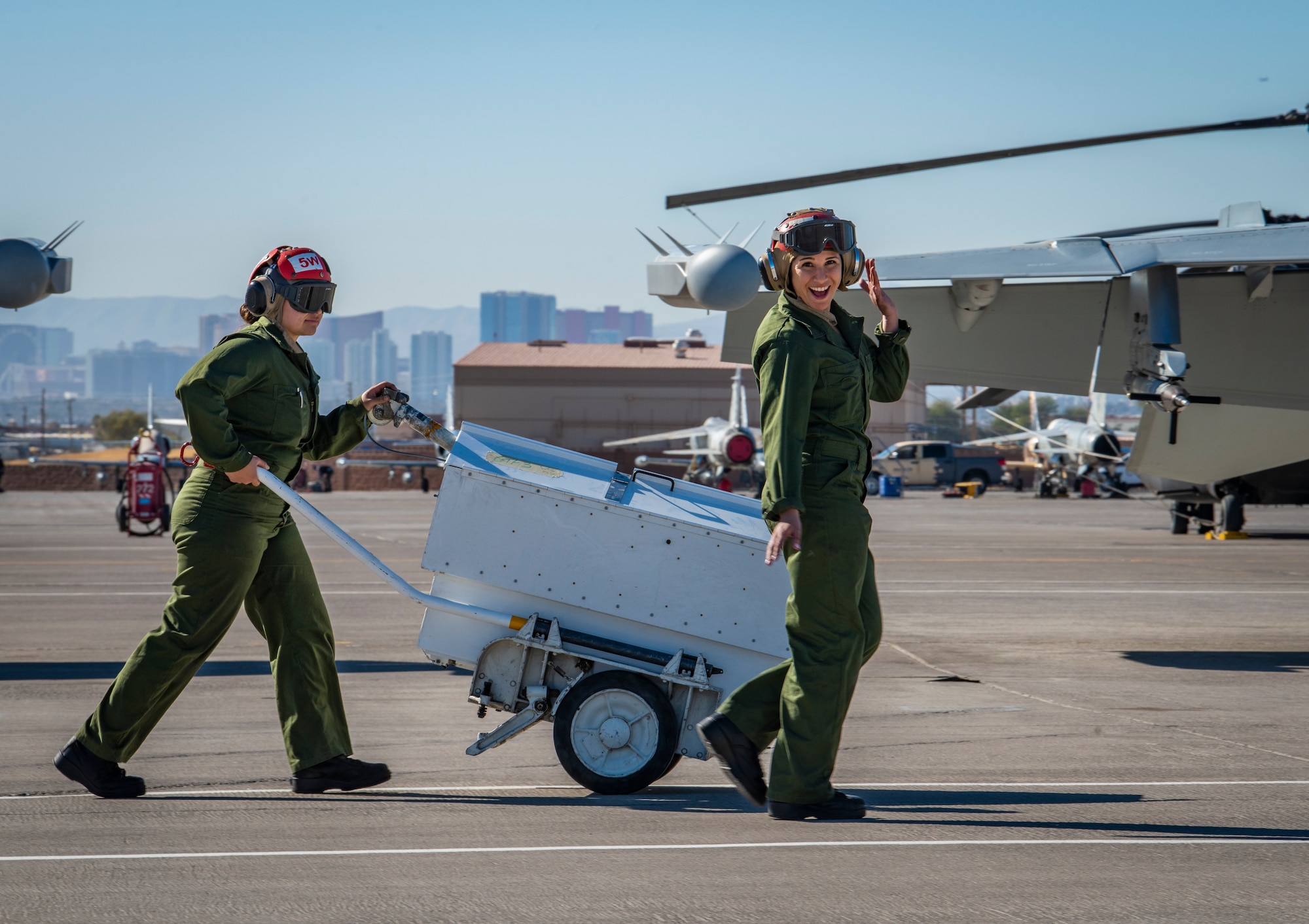 U.S. Navy Airmen walk with box on the flight line.