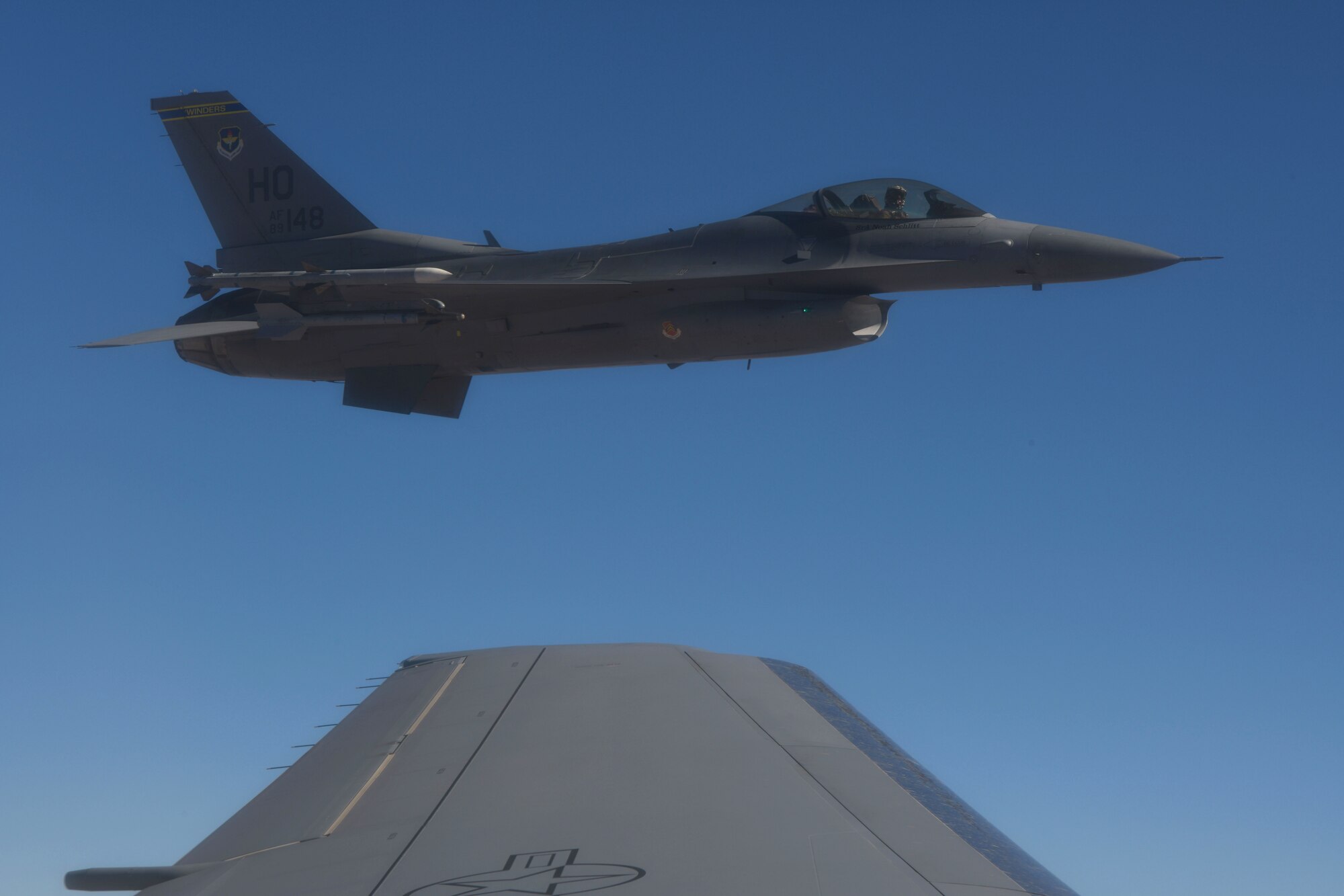 An F-16 Fighting Falcon from the 49th Wing at Holloman Air Force Base (AFB), New Mexico, flies off the left wing of a KC-46 Pegasus from the 56th Air Refueling Squadron at Altus AFB, Oklahoma, December 7, 2020. A two-ship KC-46 refueler formation flew in a racetrack pattern over southern New Mexico while refueling ten F-16s from Holloman AFB. (U.S. Air Force photo by Tech. Sgt. Robert Sizelove)