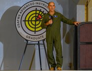 Airman stands on stage with microphone in hand