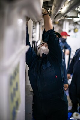 Fireman Sydney Burroughs, assigned to the Wasp-class amphibious assault ship USS Kearsarge (LHD 3), applies an emergency water activated repair patch to a chill water pipe during a flooding drill Dec. 10, 2020.