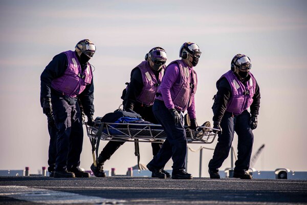 Sailors assigned to the Wasp-class amphibious assault ship USS Kearsarge (LHD 3) transport a simulated victim during a fire drill on the flight deck Dec. 10, 2020.