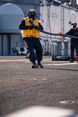 Aviation Boatswain's Mate (Handling) 2nd Class Jamie Vasquez, assigned to the Wasp-class amphibious assault ship USS Kearsarge (LHD 3), readies a hose on the flight deck during a fire drill Dec. 10, 2020.