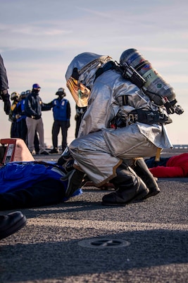Aviation Boatswain's Mate (Handling) Airman Jaaziah Hines, assigned to the Wasp-class amphibious assault ship USS Kearsarge (LHD 3), rescues a simulated victim during a fire drill on the flight deck Dec. 10, 2020.