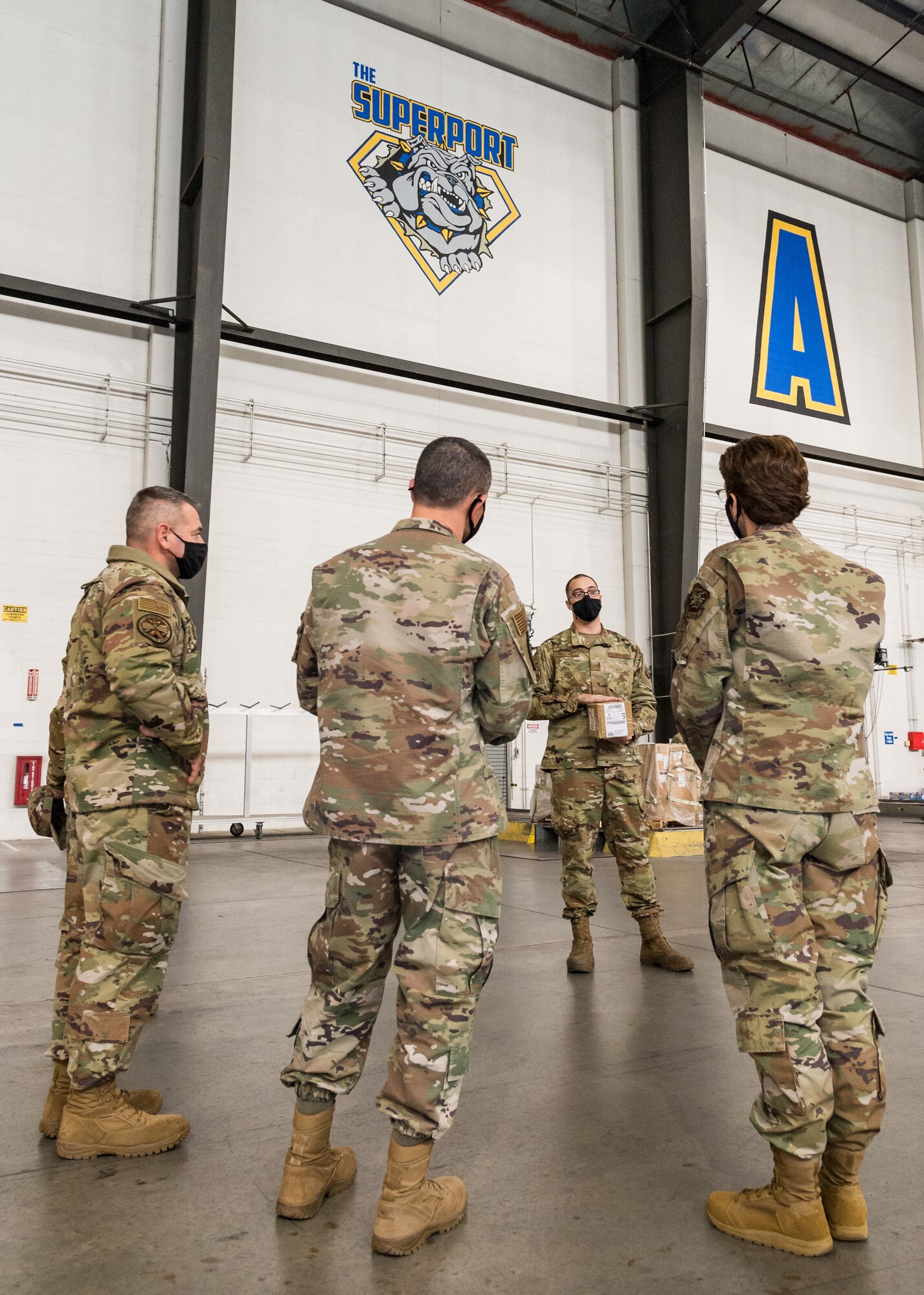 From the right, Gen. Jacqueline Van Ovost, Air Mobility Command commander; Chief Master Sgt. Brian Kruzelnick, AMC command chief; and Lt. Col. Jerry Yarrington, 436th Aerial Port Squadron commander, listen to Senior Airman Caleb Ritchie, 436th APS cargo processor journeyman, as he explains the processing and loading of cargo onto pallets at Dover Air Force Base, Delaware, Dec. 9, 2020. During their visit, Van Ovost and Kruzelnick listened to and learned from Dover Airmen, experiencing Team Dover’s missions firsthand and sharing AMC’s vision and priorities. (U.S. Air Force photo by Roland Balik)