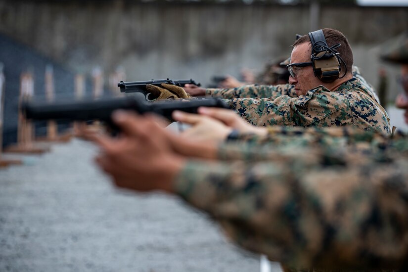 A group of Marines fire weapons toward a target.