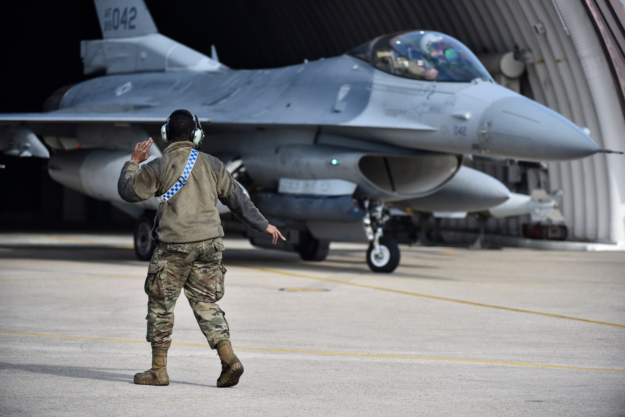 A crew chief marshalling an F-16 before flight.