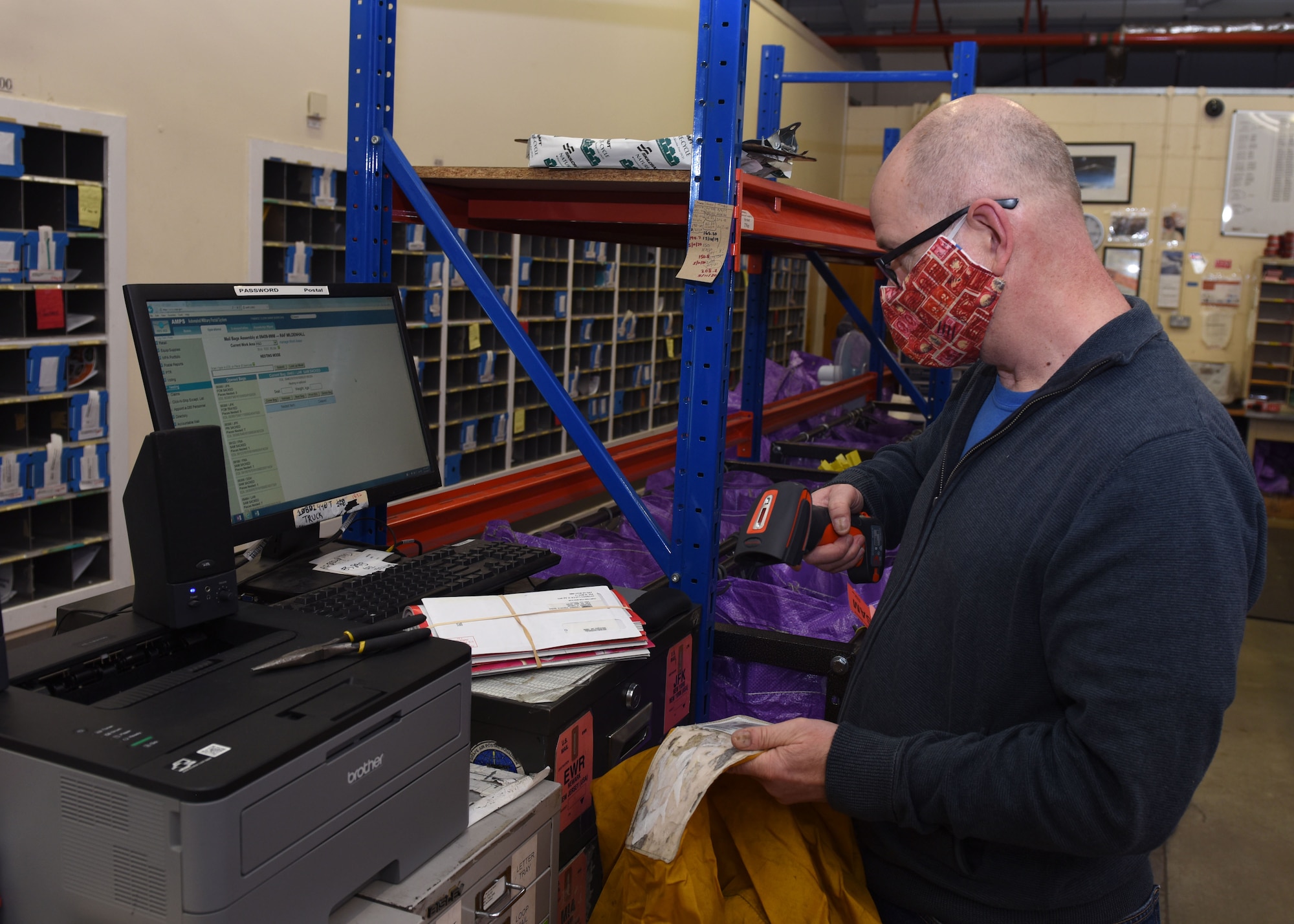 Mark Burrows, 100th Force Support Squadron Post Office assistant receipt and dispatch clerk, scans outgoing mail at Royal Air Force Mildenhall, England, Dec. 1, 2020. All mail bags are color-coded based on the type of mail and the destination. (U.S. Air Force photo by Karen Abeyasekere)