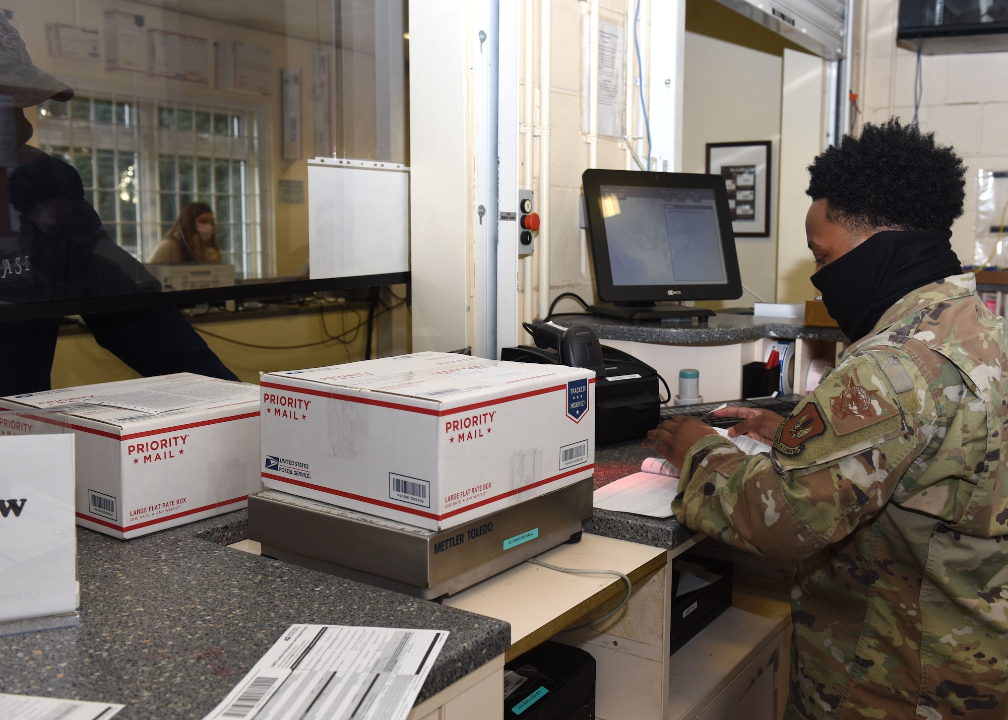 Airman 1st Class Donovan Stirling, 100th Force Support Squadron Post Office finance clerk, assists a customer with sending packages to ensure they meet U.S. Postal Service guidelines to be shipped at Royal Air Force Mildenhall, England, Dec. 1, 2020. The post office has seen a 40 percent increase in packages during the coronavirus pandemic, and an even bigger increase over the start of the holiday season. (U.S. Air Force photo by Karen Abeyasekere)