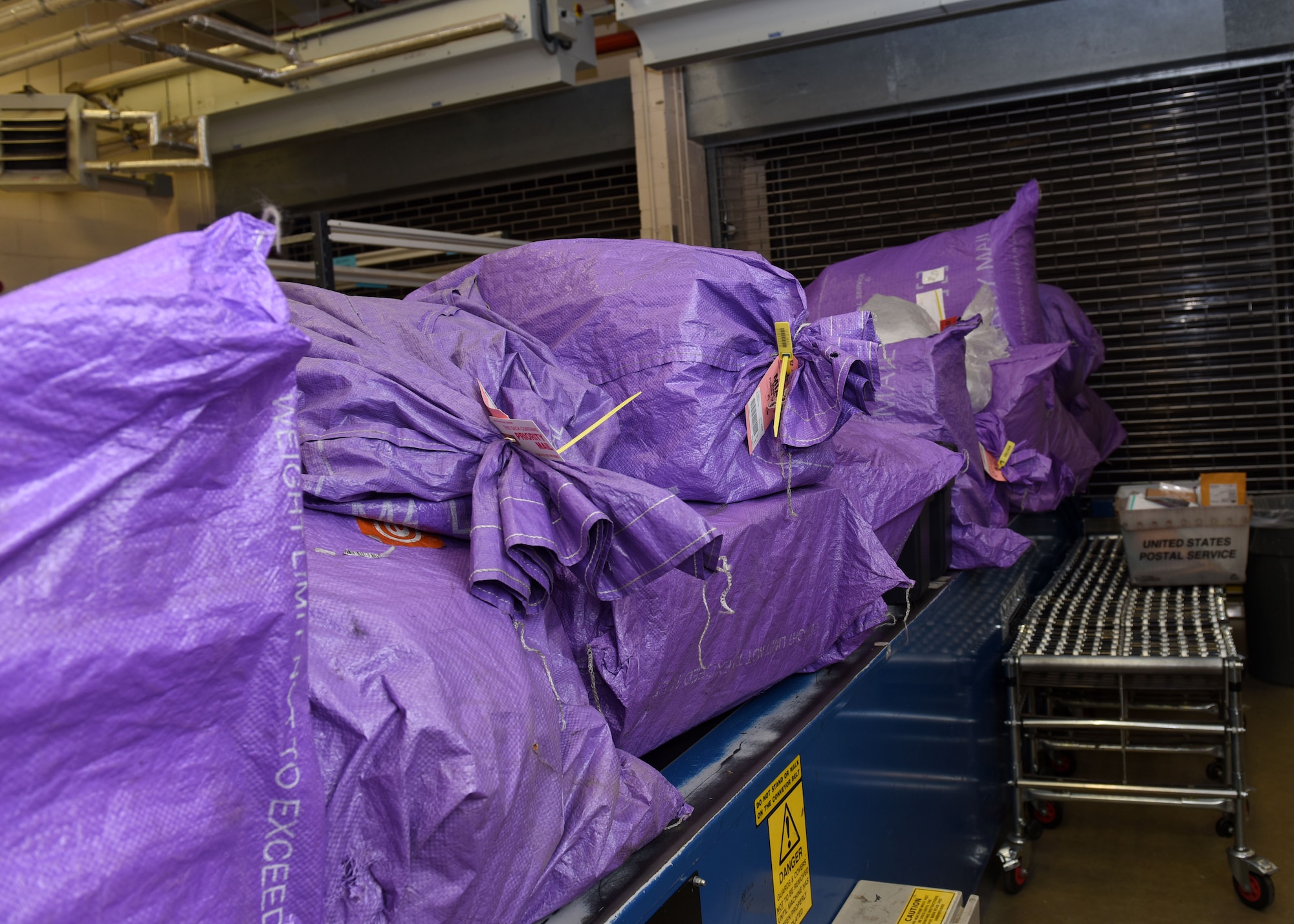 Multiple bags of outgoing mail, all received within the first 90 minutes of the post office opening, are stored, ready to be loaded onto a truck and taken to the airport for shipping overseas at Royal Air Force Mildenhall, England, Dec. 1, 2020. All mail bags are color-coded based on the type of mail and the destination. (U.S. Air Force photo by Karen Abeyasekere)