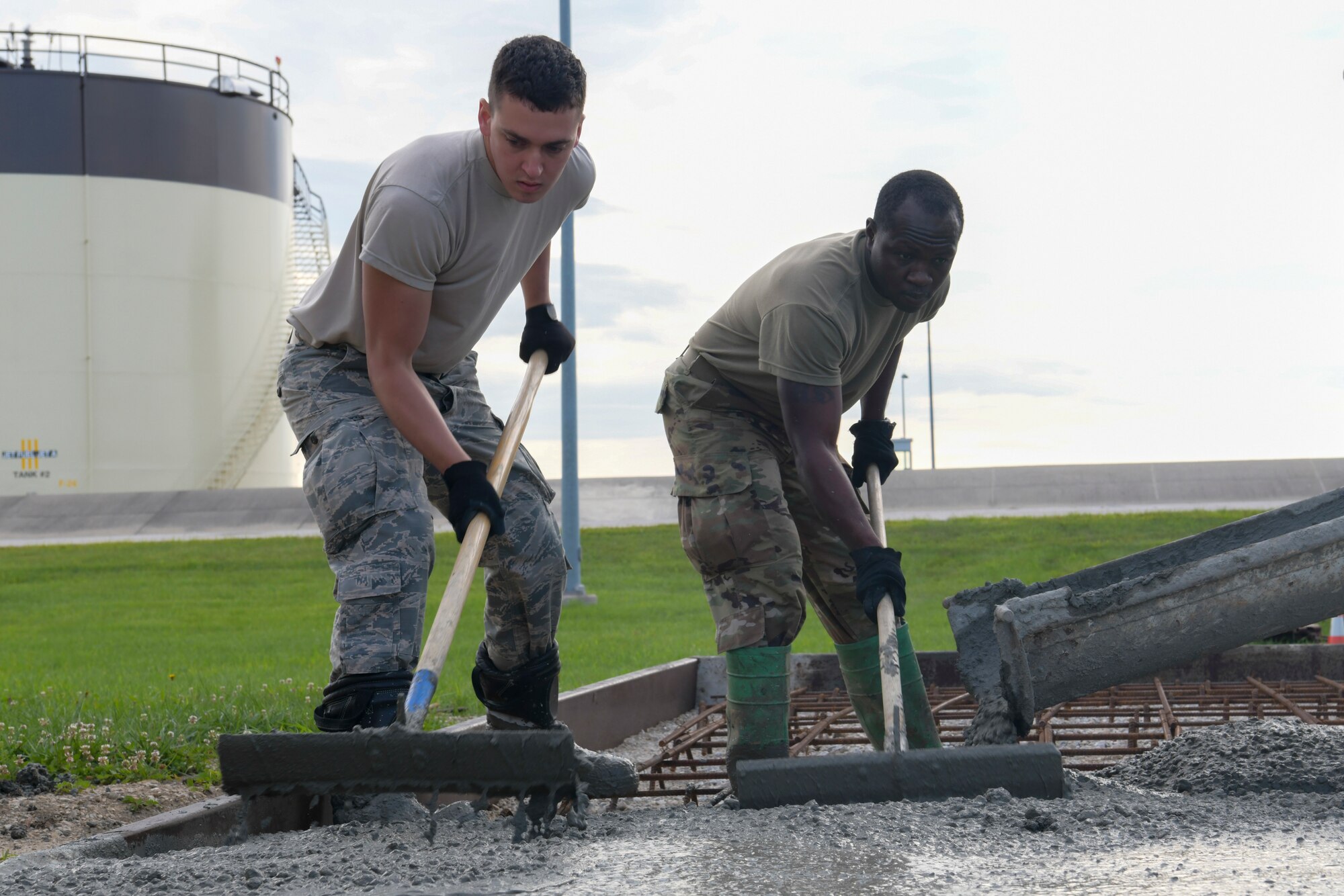U.S. Air Force Senior Airman Joshua Evans, 442nd Civil Engineer Squadron structures journeyman, left, and Airman 1st Class Melvin Sirleaf, 509th Civil Engineer Squadron structures apprentice, spread concrete for a new construction project for a new generator at Whiteman Air Force Base, Missouri, Aug. 6, 2020. The project was an opportunity for Airmen to train in unique aspects of their jobs, which are normally performed overseas. (U.S. Air Force photo by Staff Sgt. Dylan Nuckolls)