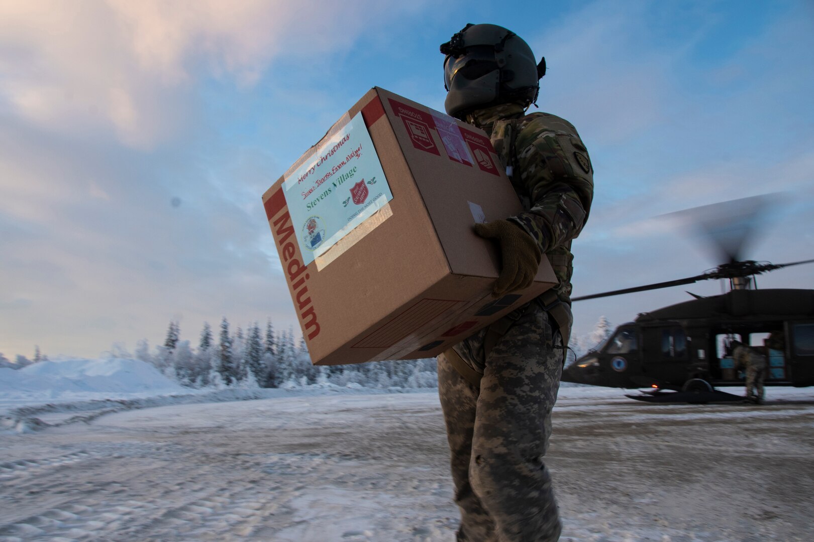 Sgt. Peter Phillip, Alaska National Guard UH-60 Black Hawk crew chief, delivers packages as a part of the 65th annual tradition of Operation Santa Claus. This year, the Alaska National Guard brought gifts and supplies for people in the remote Alaskan villages of Stevens Village, Birch Creek and Nanwalek.