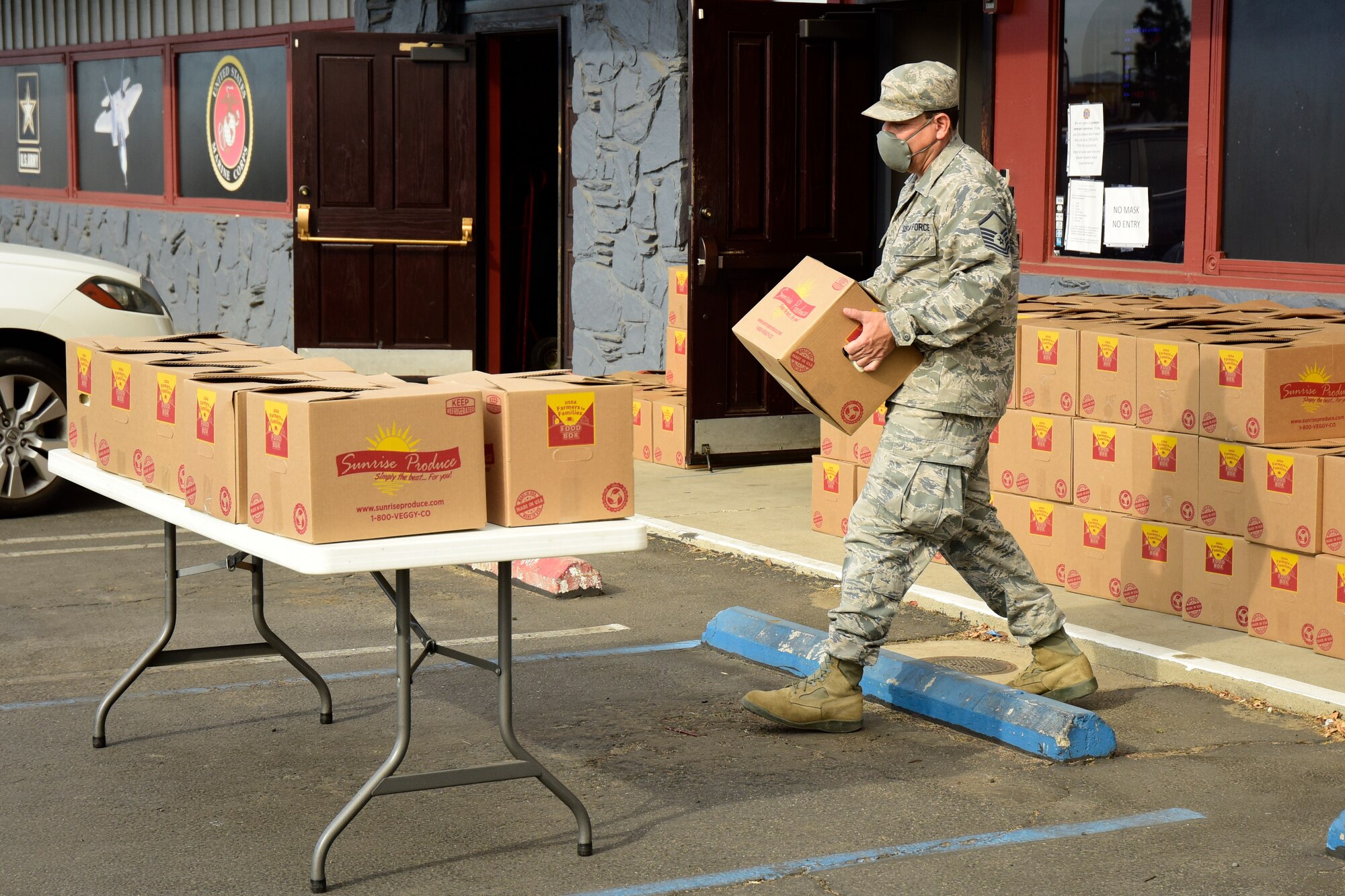 U.S. Air Force Master Sgt. Carlos Coronado, 210th Weather Flight, 163d Attack Wing, California Air National Guard, stages food boxes on a table for an event at the Veterans of Foreign Wars Post 8547, Moreno Valley, California, Dec. 9, 2020. Over 150 food boxes were provided by the Community First Church of God in Homeland, California, as part of the U.S. Department of Agriculture Farmers to Families Food Box Program. (U.S. Air National Guard photo by Senior Airman Neil Mabini)