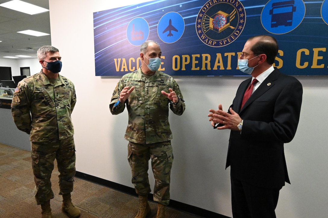 Two senior army leaders wearing face masks greet a civilian wearing a face mask.