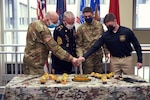 Army Maj. Gen. Raymond Shields, the adjutant general of New York; retired Army Sgt. Maj. Christian Glorius; Air Force Senior Airman Caleb Lapinel and Army Pvt. Malachy McGarry cut the National Guard birthday cake during a ceremony celebrating the 384th birthday of the National Guard at New York National Guard Joint Force Headquarters, Latham, N.Y., Dec. 14, 2020.