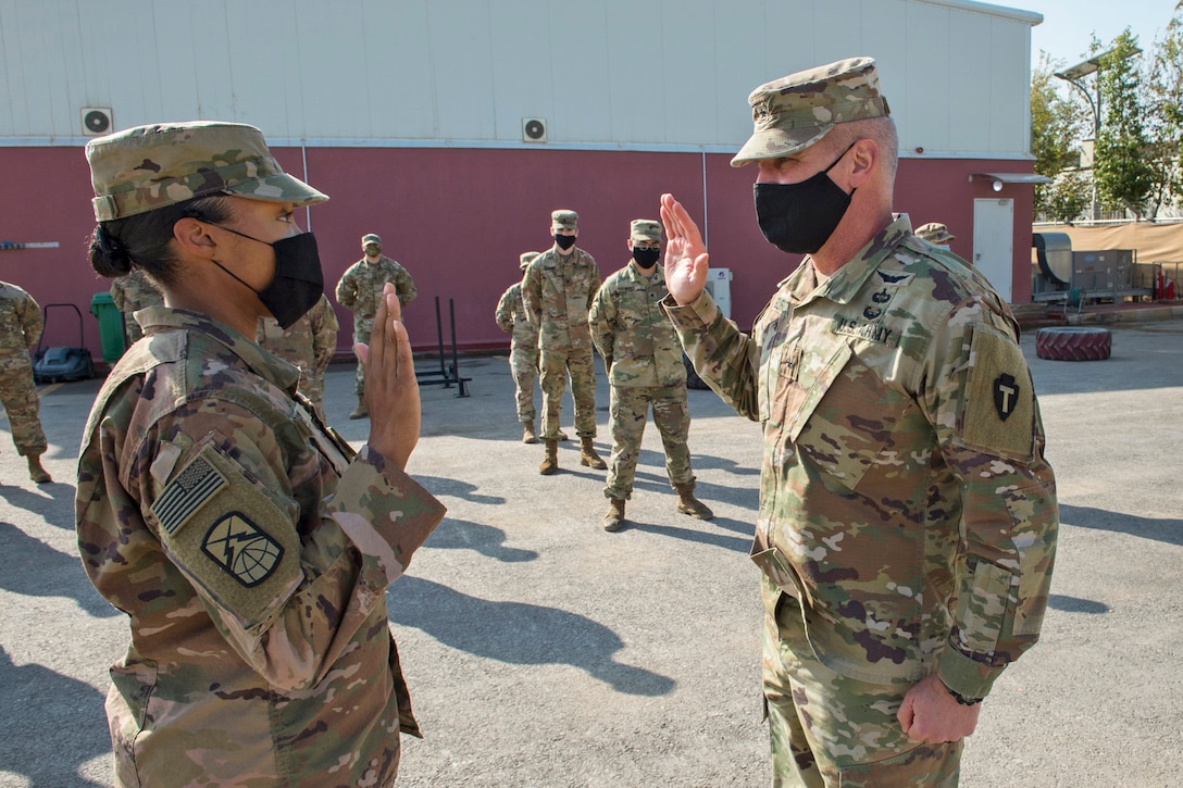Two soldiers face each other with raised right hands.