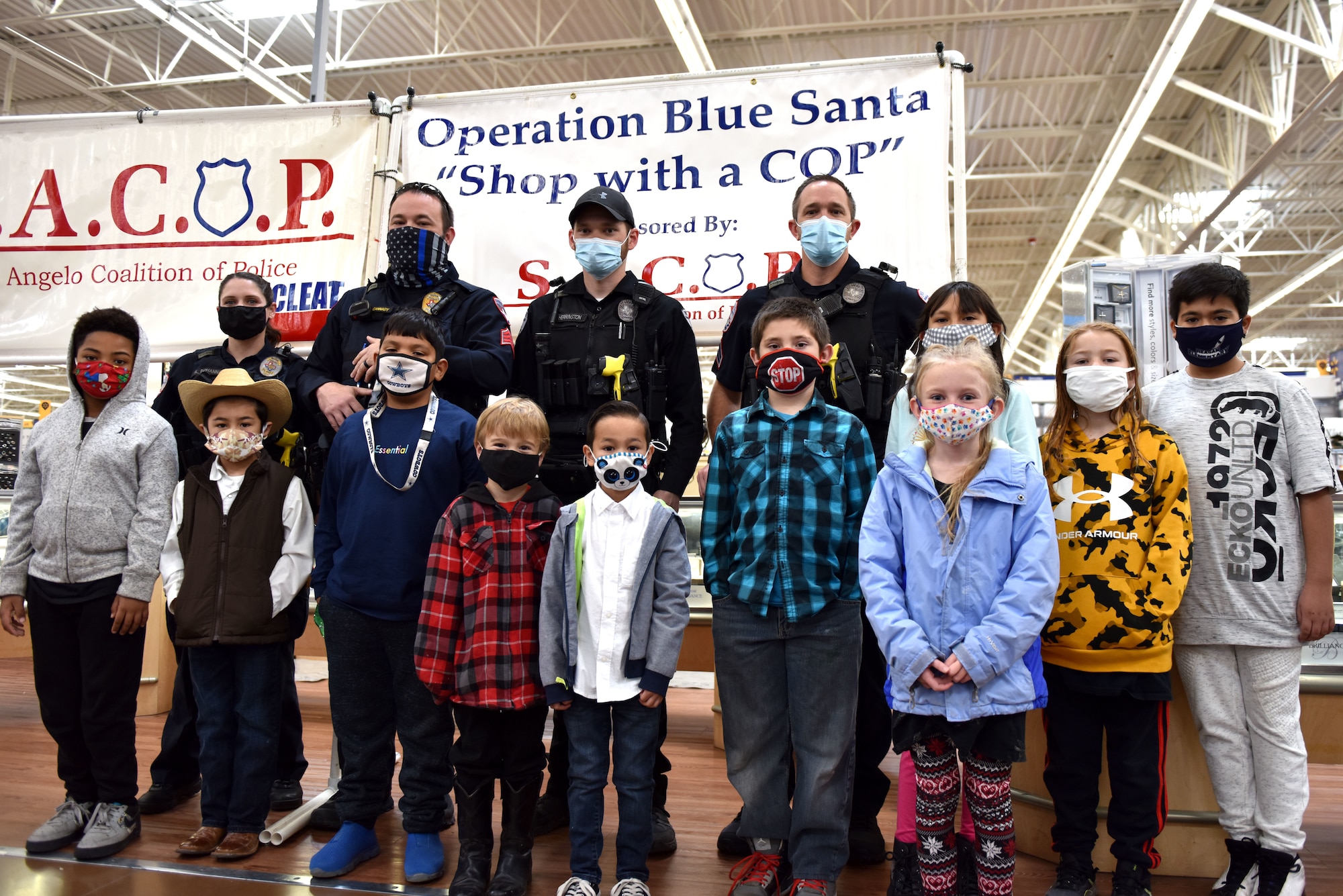 San Angelo Police Department volunteers pose with the first wave of children selected to participate in the 13th Annual Operation Blue Santa event in San Angelo, Texas, Dec. 12, 2020. After taking pictures with the police officers the children shopped for gifts for themselves and their families. (U.S. Air Force photo by Staff Sgt. Seraiah Wolf)