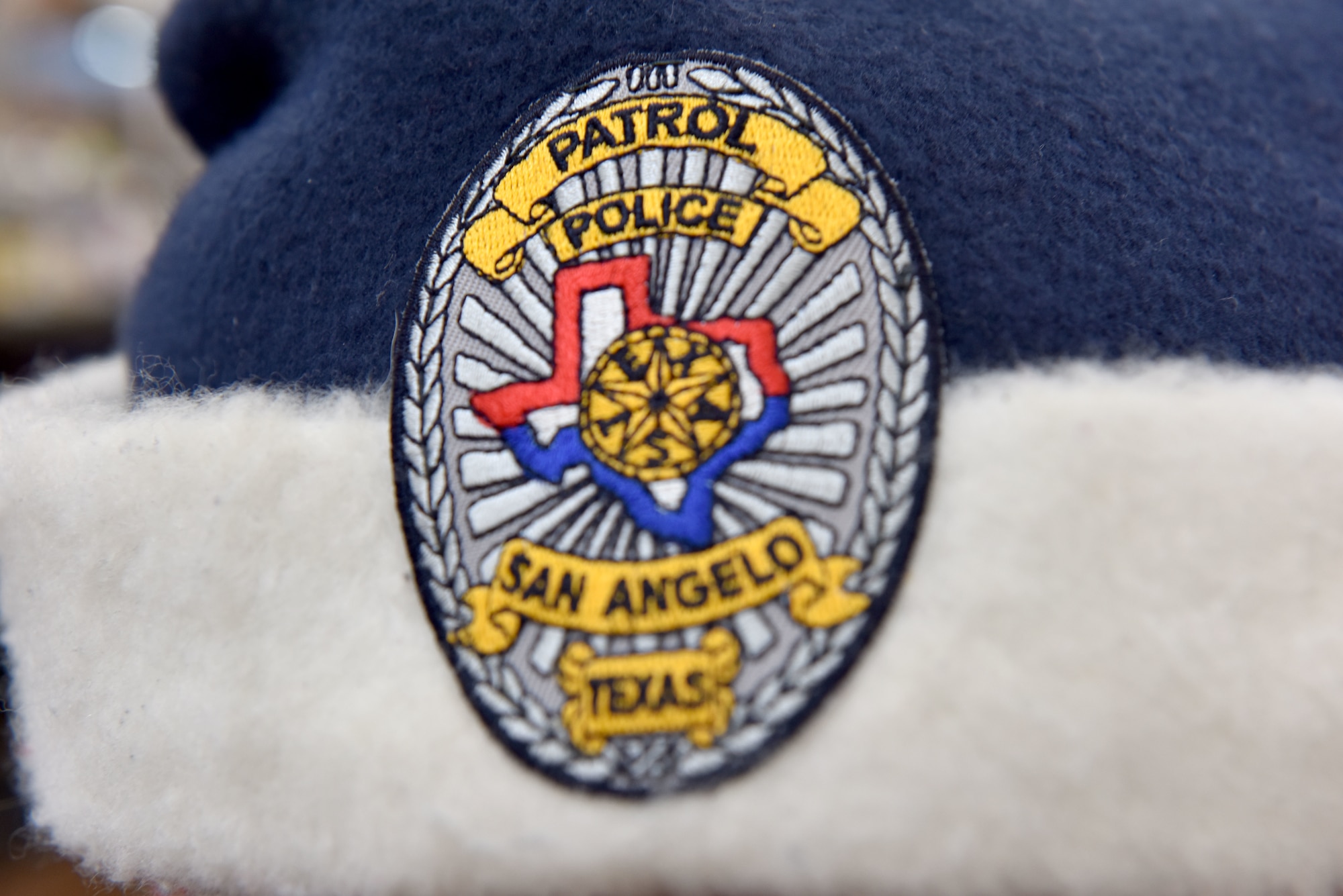 A police officer participating in the 13th Annual Operation Blue Santa shows off his blue Santa hat complete with a San Angelo police badge in San Angelo, Texas, Dec. 12, 2020. This year, many children safely participated in the event with COVID-19 restrictions. (U.S. Air Force photo by Staff Sgt. Seraiah Wolf)