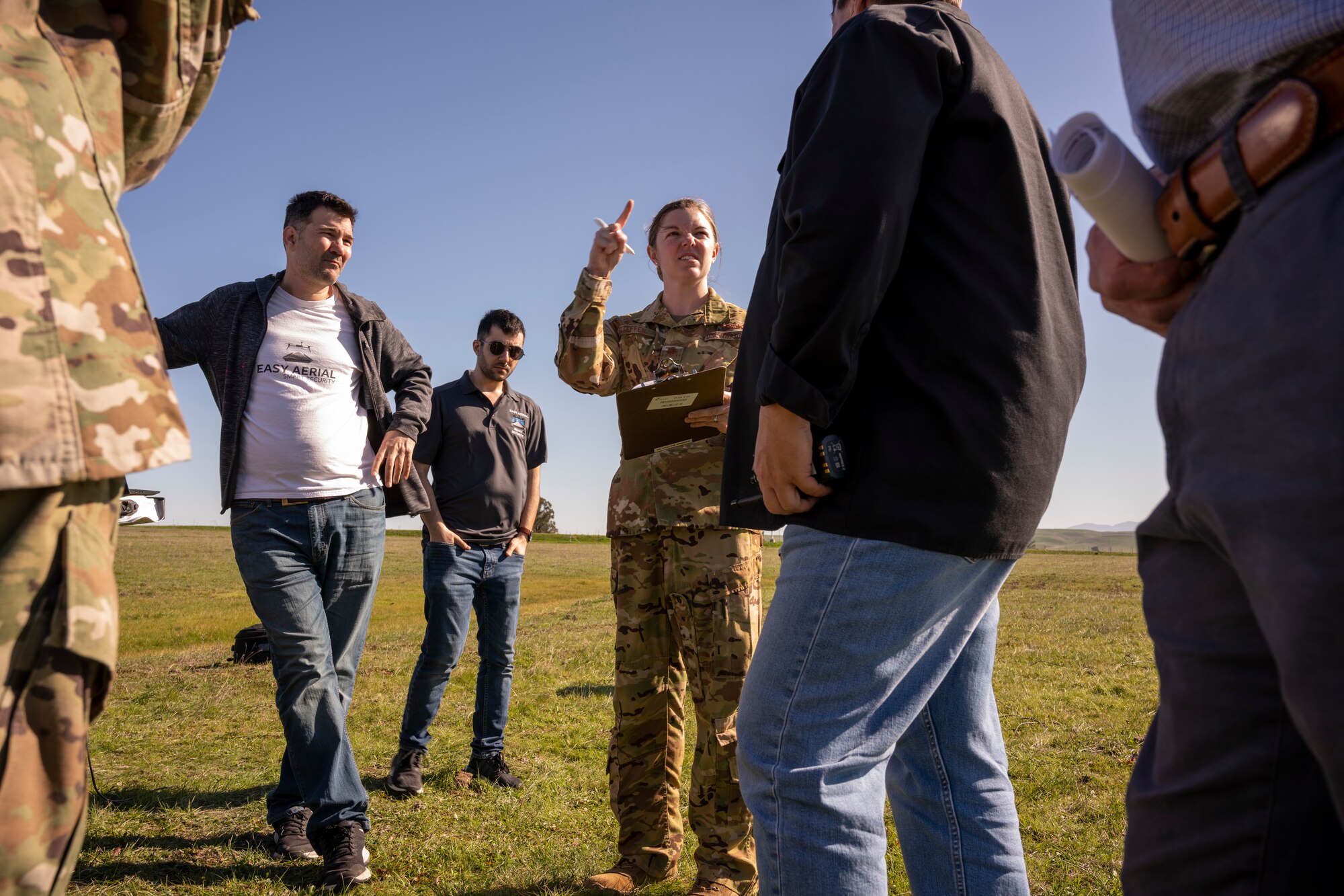 A woman in the Air Force talks to civilian personnel in a group.